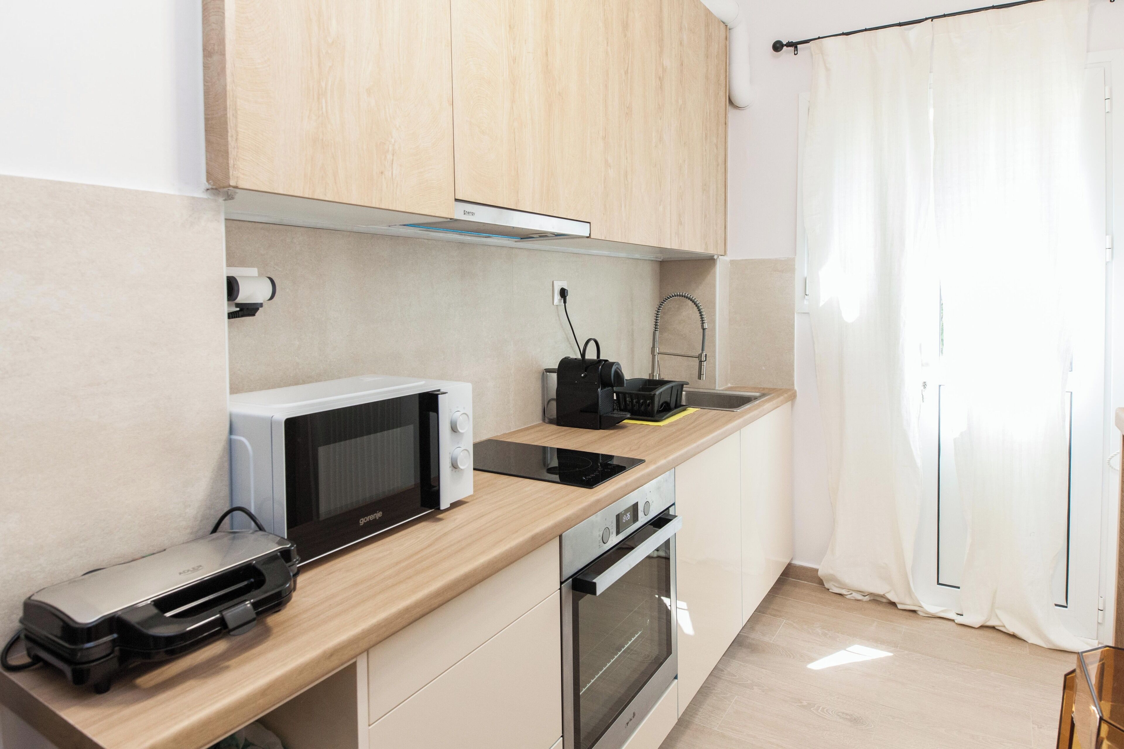 A modern kitchen with wooden cabinets, a microwave, a coffee maker, and a dishwasher.