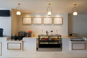A modern reception area with a marble counter, framed artwork on the wall, and pendant lighting. - 1O1 URBAN Jakarta Glodok - Kota Tua (West Jakarta)