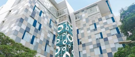 Ein modernes Gebäude mit einer geometrischen Fassade und einem markanten vertikalen Element. Auf dem Schild steht 'ICANURBAN'.