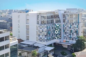 En modern byggnad med flera våningar, ett iögonfallande rutmönstrat fasad, en framträdande logotyp och en väl synlig entré.