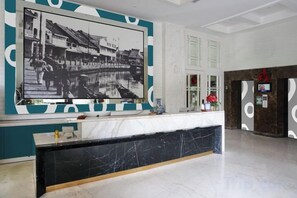 A reception area with a marble counter, a large black and white photograph, and a modern reception desk. - 1O1 URBAN Jakarta Glodok - Kota Tua (West Jakarta)