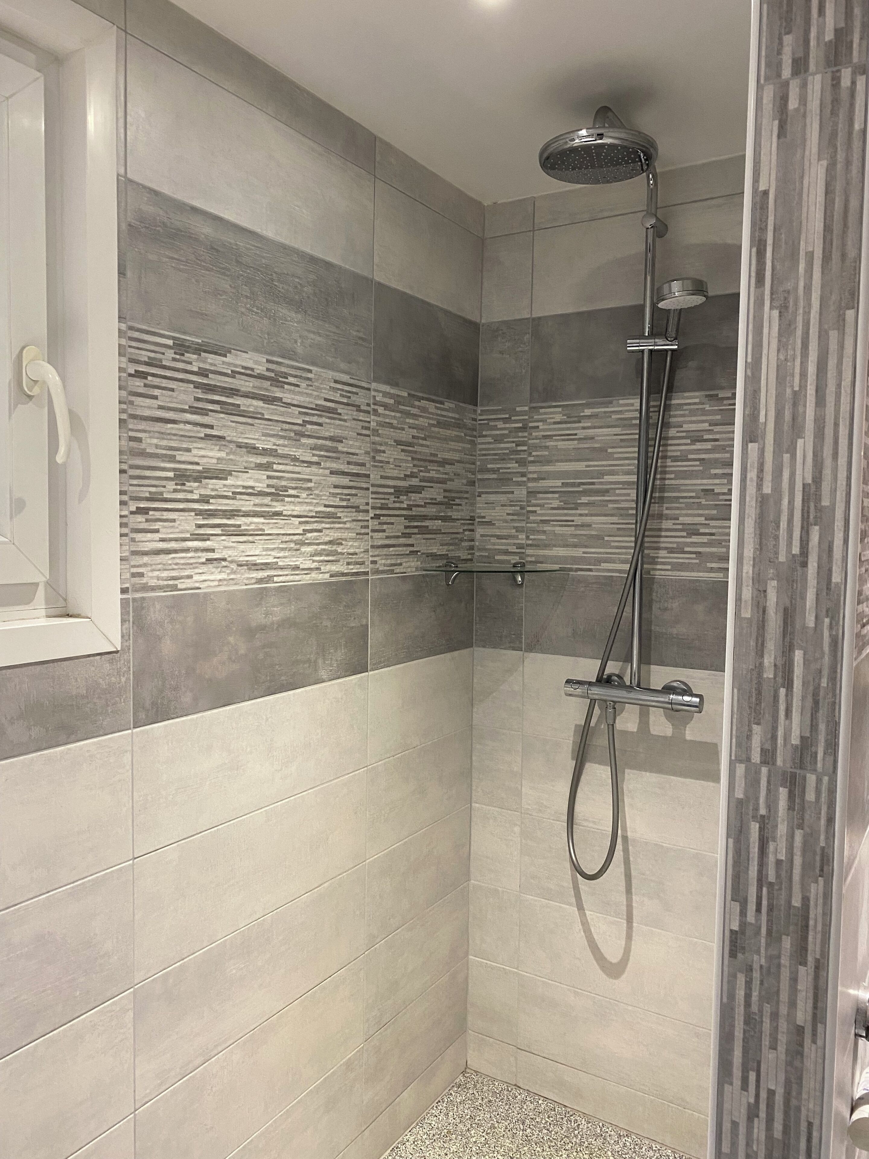 A modern shower with a rain showerhead, a handheld showerhead, and a glass-enclosed shower area.