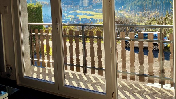 Una habitación con amplios ventanales que ofrecen vistas a un paisaje montañoso y un estacionamiento.