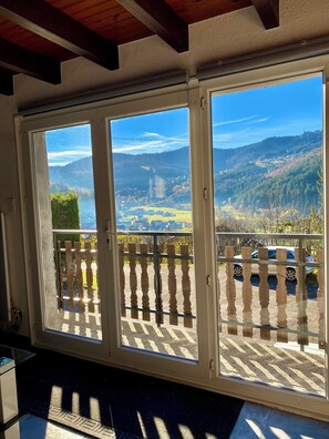 A room with large windows offering a view of a mountainous landscape and a parking area.