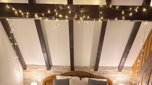 Un dormitorio con una cama de madera, ropa de cama blanca y luces de cuerda.