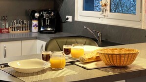 Una cocina moderna con armarios blancos, encimera negra y un comedor con una cesta de pan.