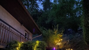 Un escalier agrémenté de luminaires décoratifs, un bâtiment doté d’un balcon et des arbres en arrière-plan.