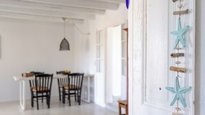 Un coin repas avec une table et des chaises blanches, un luminaire suspendu et une étoile décorative sur le mur.