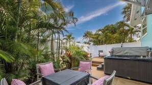 Une terrasse extérieure avec une table et des chaises, entourée d’une végétation luxuriante et de palmiers.