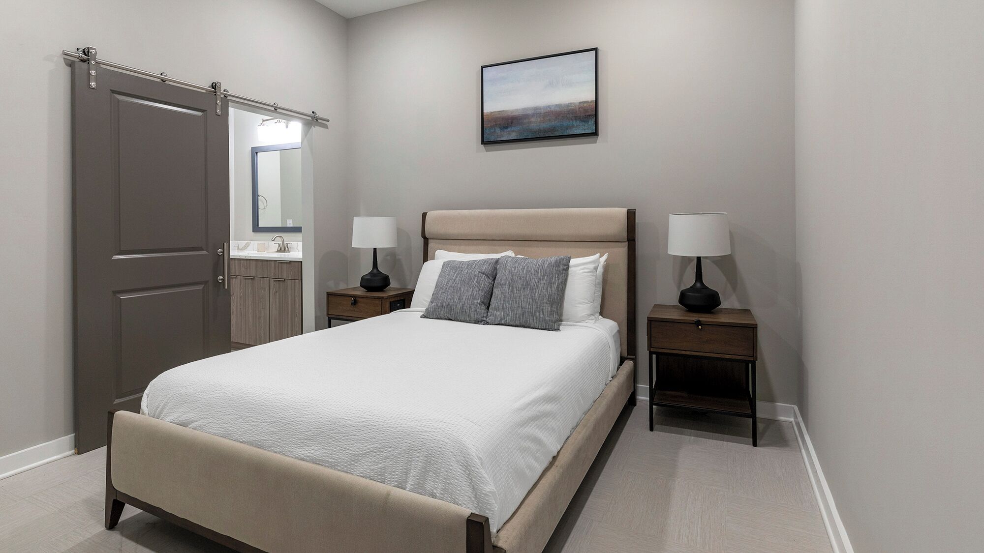 Une chambre à coucher comprenant un lit, deux tables de chevet, une commode, une armoire, un miroir et un tableau accroché au mur.