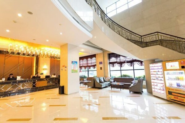 A spacious lobby with a reception desk, seating area, vending machine, and a staircase. - Guomao Hotel (Yichang)