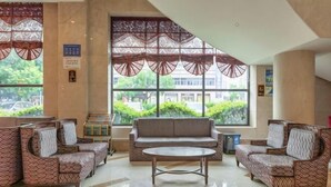 A lobby with patterned sofas, a central coffee table, and large windows with decorative screens. - Guomao Hotel (Yichang)