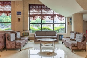 A lobby with patterned sofas, a central coffee table, and large windows with decorative screens. - Guomao Hotel (Yichang)
