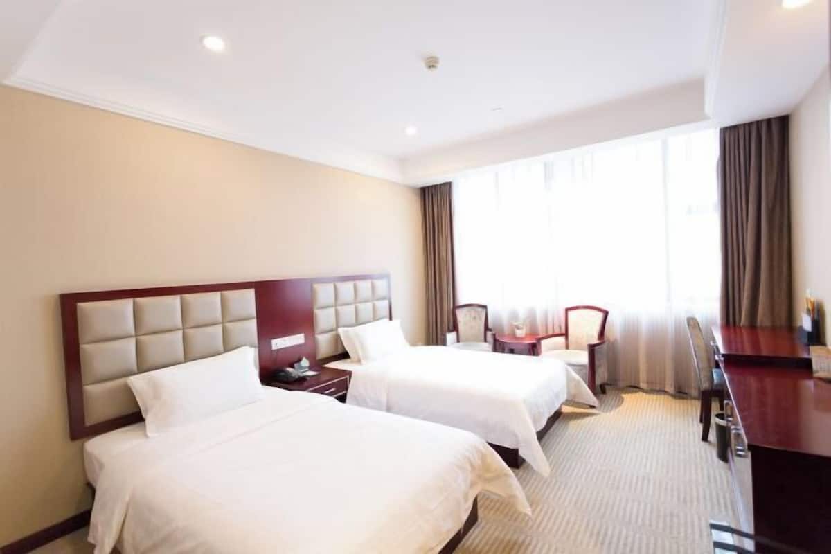 A hotel room with two beds, a desk, and a chair.