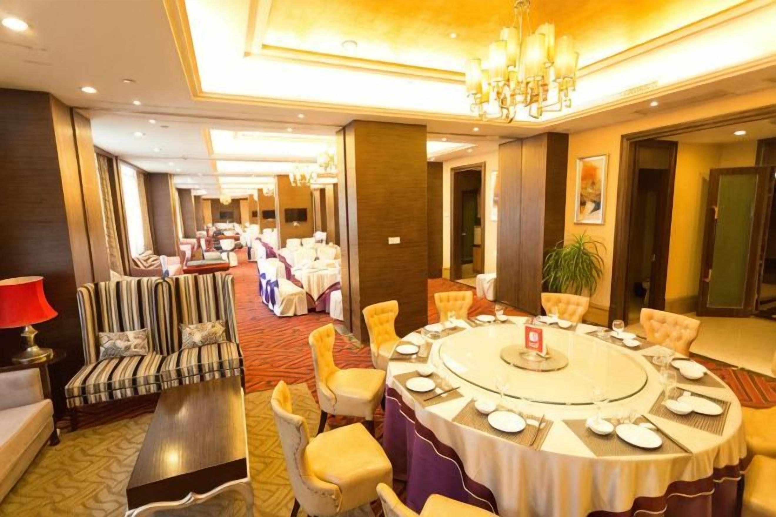 A hotel conference room with a round table, chairs, and a sofa.