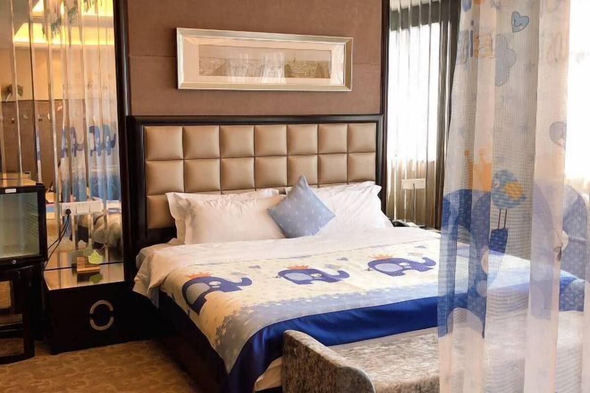 A hotel room with a large bed, a headboard, a bedside table, and a mirror.