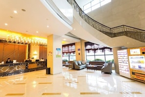 Un hall de hotel con mostrador de recepción, zona de estar y una escalera.