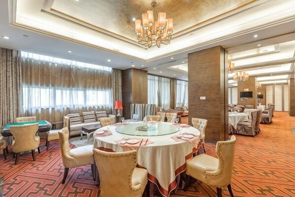 A hotel dining area with a round table, chairs, and a pool table.