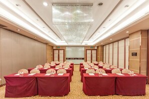 A conference room with rows of tables, chairs, and a large chandelier. - Guomao Hotel (Yichang)