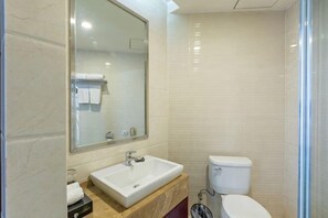 A bathroom with a white sink, mirror, and toilet. - Guomao Hotel (Yichang)