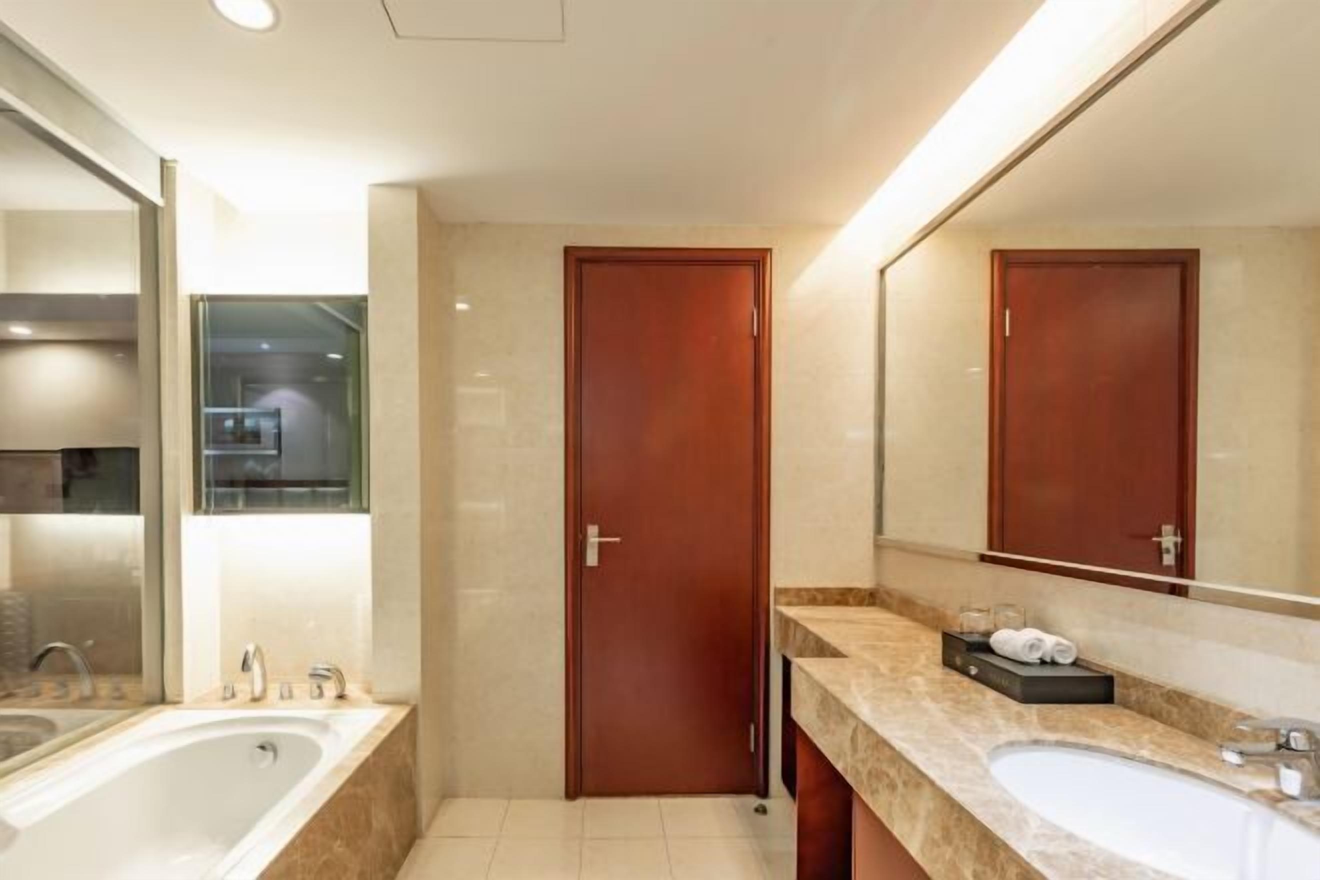 A modern bathroom with a bathtub, a sink, a mirror, and a door.