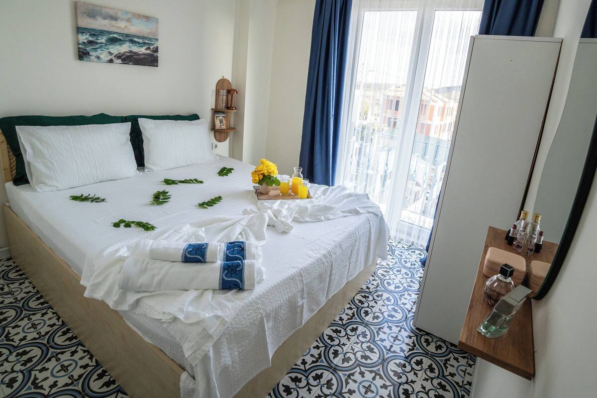 A neatly made bed with a white bedspread, a wooden headboard, and a blue and white patterned floor.