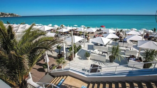 Ein Strandhotel mit Außenbereichen, Palmen und Blick auf das Meer.