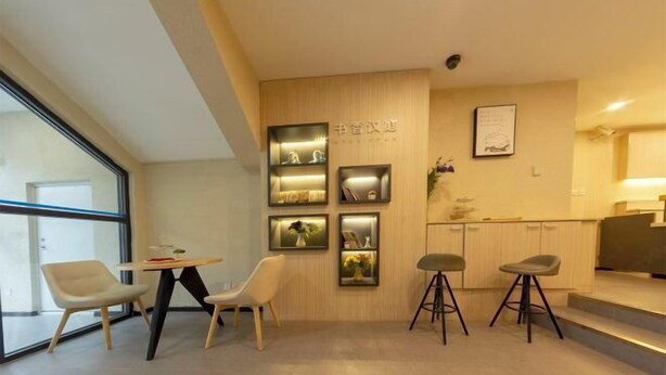 A modern interior with a dining area, wall-mounted shelves with decorative items, and a kitchen area. - HanTing Hotel (Jilin Street Railway Station) (Jilin City)