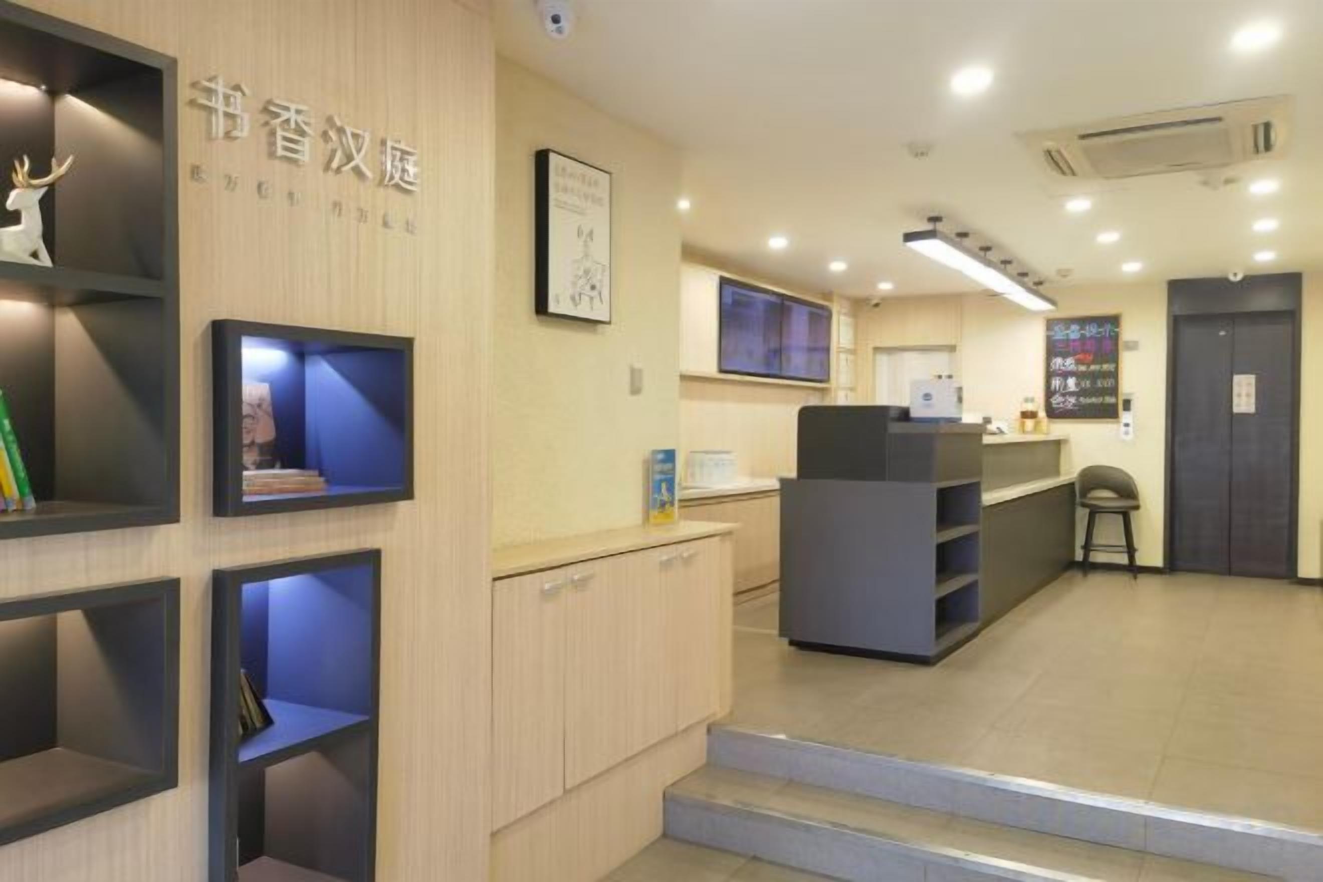 A reception area with a counter, shelves with items, and a staircase leading to an upper level.