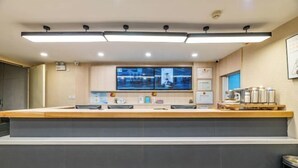 A modern reception desk with a flat-screen TV, a coffee machine, and a trash bin. - HanTing Hotel (Jilin Street Railway Station) (Jilin City)