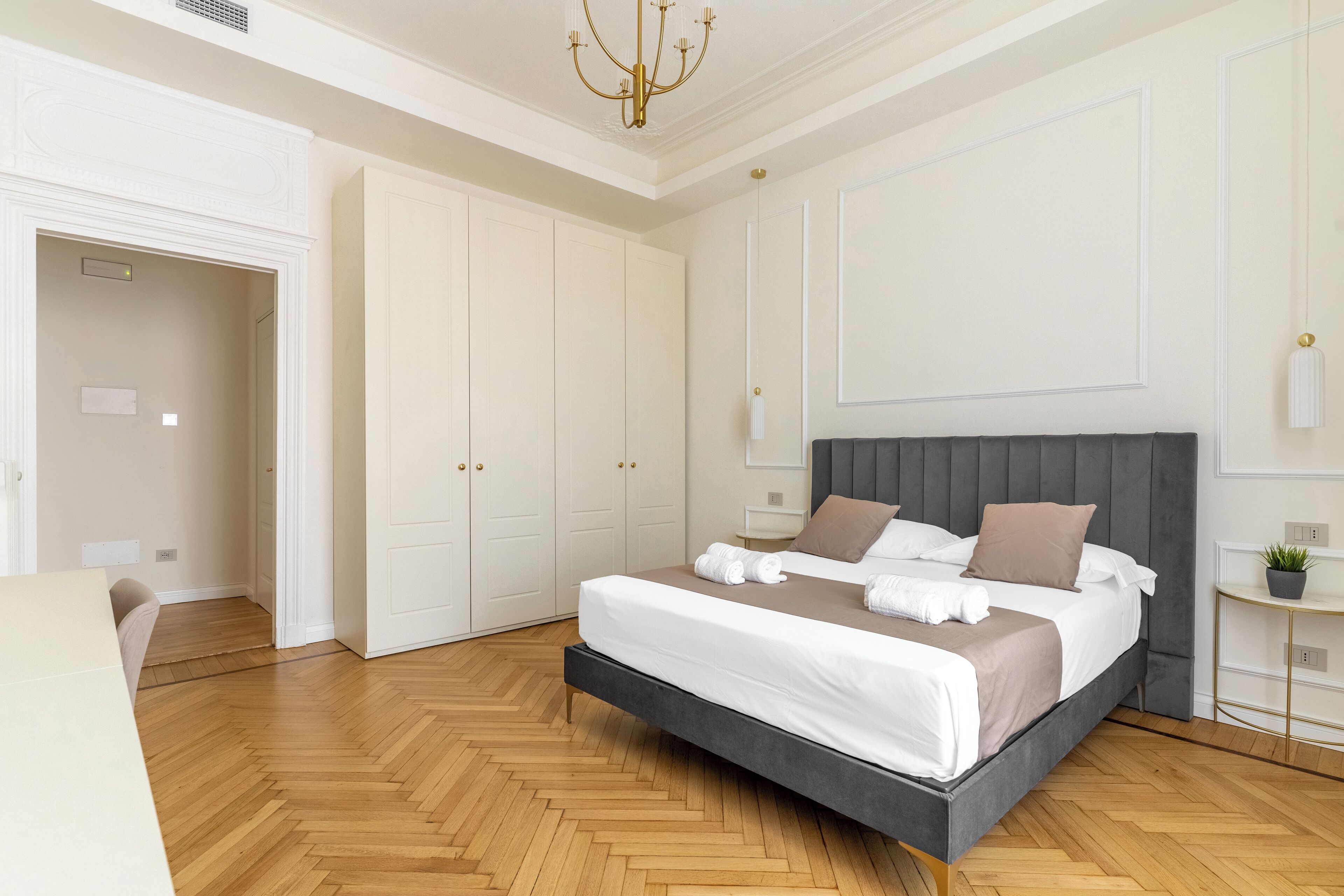 Une chambre à coucher moderne avec un grand lit, une commode, une table de chevet et un lustre.