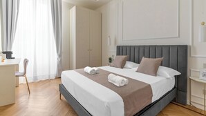 A modern hotel room with a large bed, a desk, and a chair. - Montello Suites Foresteria Lombarda (Milan)