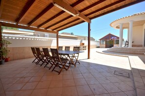 Relax in style with a round table and six comfortable chairs under a shaded pergola.