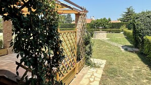 A garden with a pergola, stone pathway, and well-maintained hedges.
