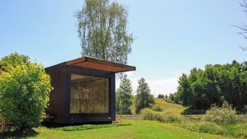 A modern, single-story building with a large glass window, surrounded by a grassy area and trees.