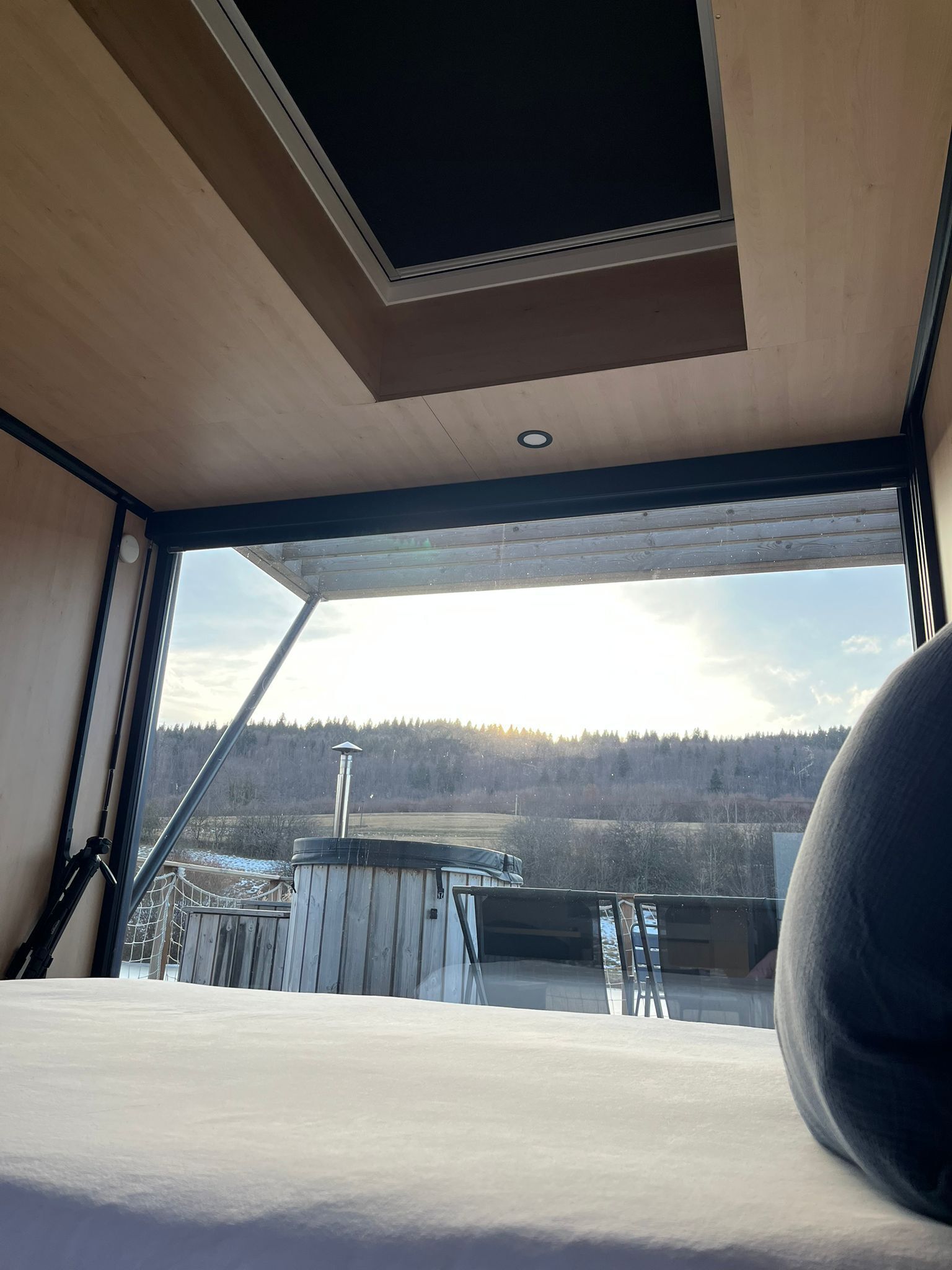 A room with a large window offering a view of a forested landscape.