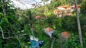 Un resort tropical con piscina, exuberante vegetación y varios edificios con techos rojos.