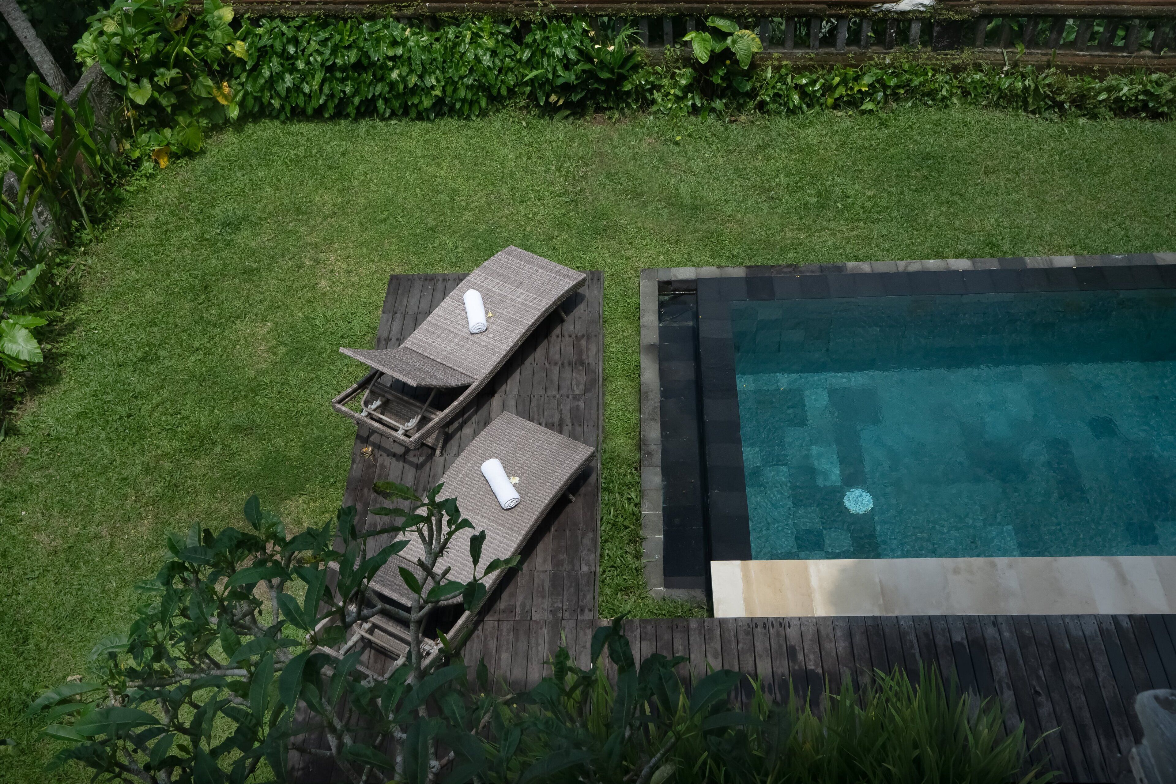 A swimming pool with a wooden deck and two lounge chairs.