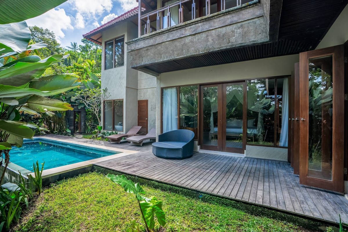 Una casa moderna con piscina, terraza de madera y grandes puertas de vidrio.