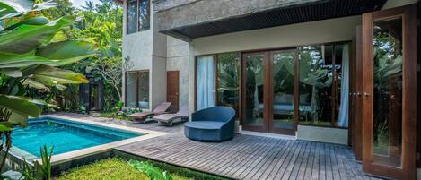 A modern house with a swimming pool, wooden deck, and large glass doors.