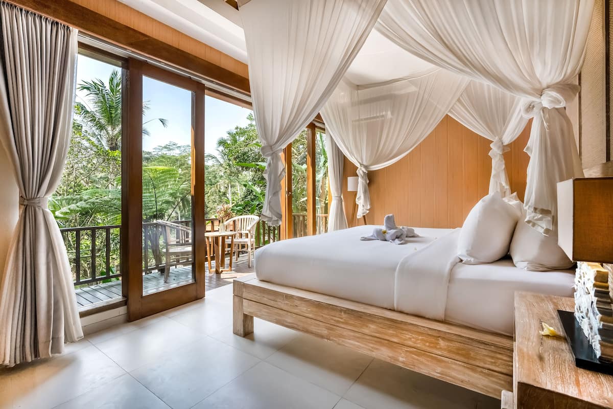 Un dormitorio con una cama grande, cabecera de madera y vistas al exterior.