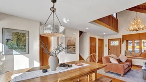 Un espace de salle à manger moderne avec une table en bois, un vase orné de branches et un lustre.
