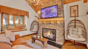 Un salon chaleureux avec une cheminée en pierre, des fauteuils confortables et un téléviseur fixé au-dessus.