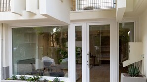A modern building entrance with glass doors, a stone-paved area, and potted plants. - DimmiDiRimini (Rimini)