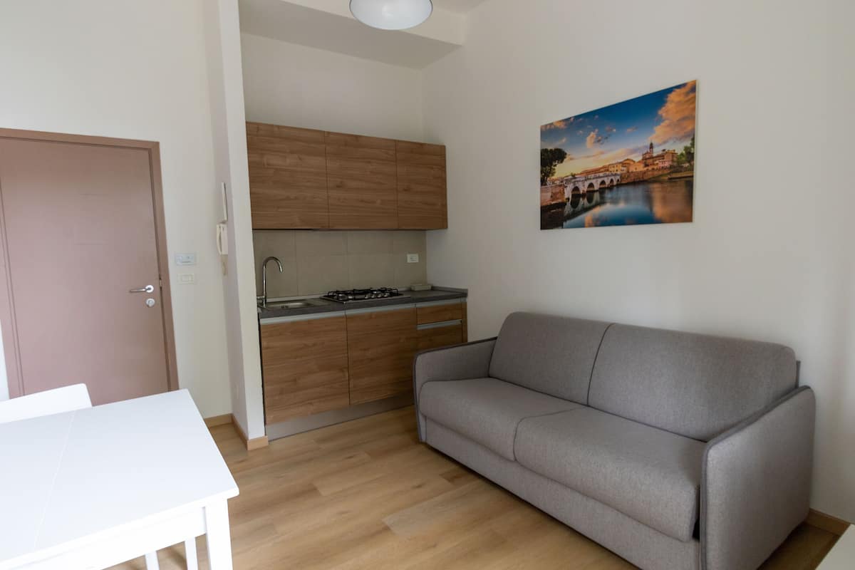 Un espacio habitable compacto con kitchenette, un sofá y una mesa de comedor.