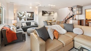 Una sala moderna con un sofá, sillones y un comedor.