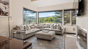 A modern living room with a large L-shaped sectional sofa, a dining table with chairs, and a fireplace.