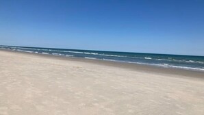 Een strand met een heldere lucht en een kalme zee.