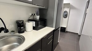 Una cocina moderna con un lavamanos de acero inoxidable, una cafetera, un microondas y un refrigerador.