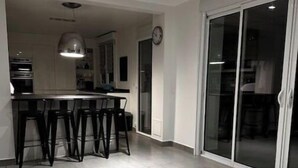 Een moderne keuken met een centraal kookeiland, barstoelen en een hanglamp.